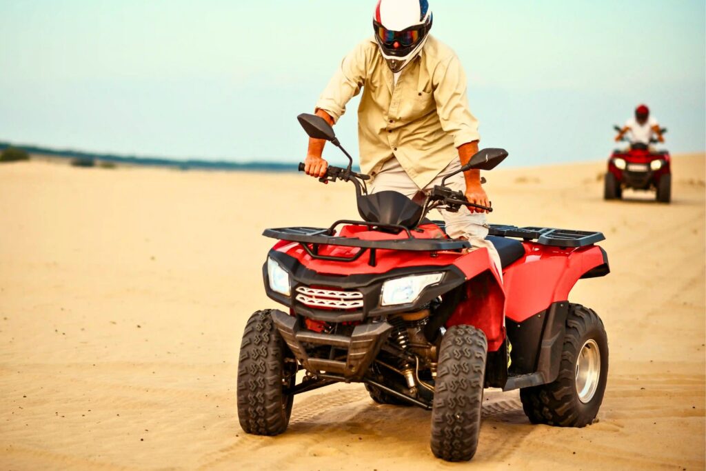 a man riding a quad bike in the desert of abu dhabi and enjoying a quad bike desert safari abu dhabi trip